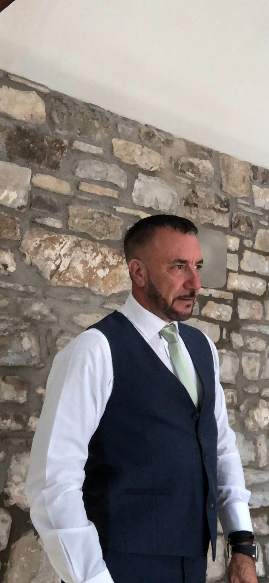 Mark John Eckley photographed against a stone wall in a tailored waistcoat